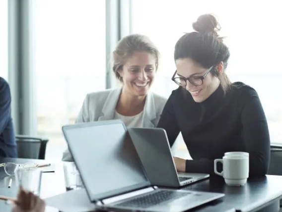 Smiling colleagues looking at a laptop 