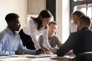 A manager leads a meeting of four other employees